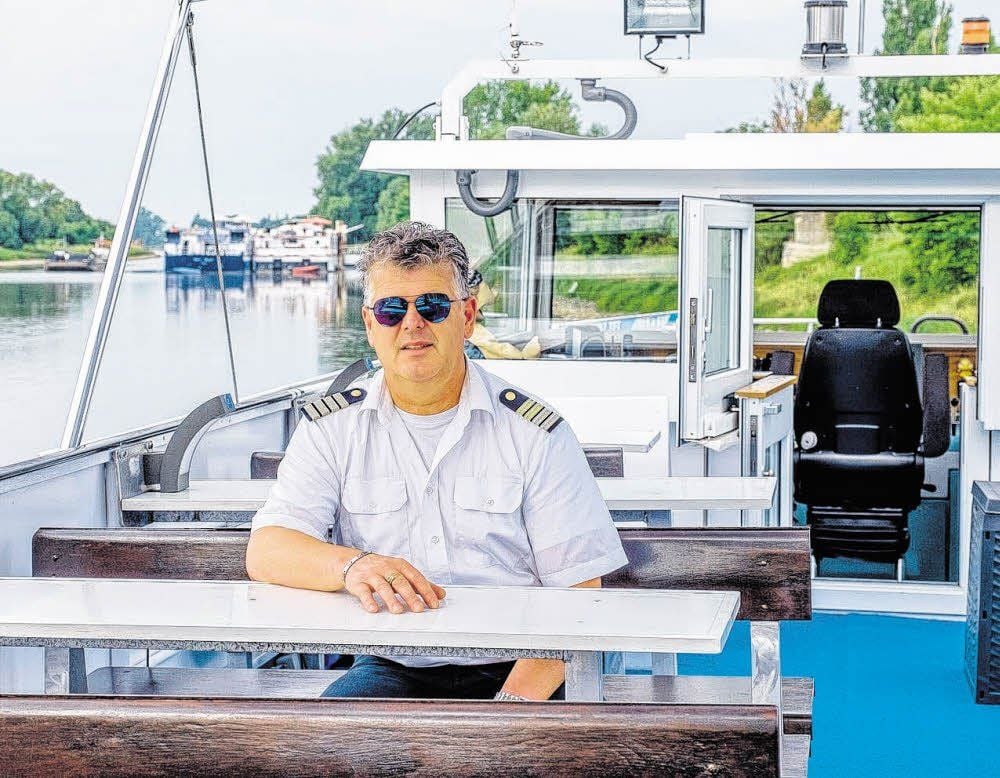 Jan Harnisch auf seinem Schiff, im Hintergrund zwei der drei festliegenden Kreuzfahrtschiffe.