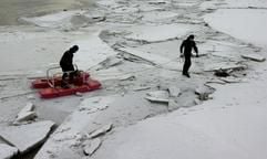 Feuerwehr-Taucher und Sprengexperten der Polizei bereiten am Sonntag (12.01.2003) bei Heirothsberge östlich von Magdeburg eine Sprengung einer riesigen Eisfläche auf dem Elbe-Umflutkanal vor. Dabei benutzen sie einen Sicherheitsschlitten. Die Eisbarriere auf dem Elbe-Umflutkanal behindert den Abflus des Hochwassers und bedroht eine Brücke der Bundesstraße 1. (Foto: dpa)