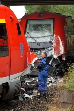 Ein Mitarbeiter der Sicherungsgruppe der Polizei betrachtet die beiden stark beschädigten Nahverkehrszüge, die am Sonntag (28.09.2003) nahe Holzdorf bei Weimar zusammengestoßen waren. (Foto: dpa)