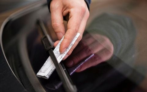 Ein Mitarbeiter des Schweriner Ordnungsamtes steckt am 17.12.2012 in der Innenstadt von Schwerin (Mecklenburg-Vorpommern) einen Strafzettel (Knöllchen) unter den Scheibenwischer eines Autos. (FOTO: DPA)