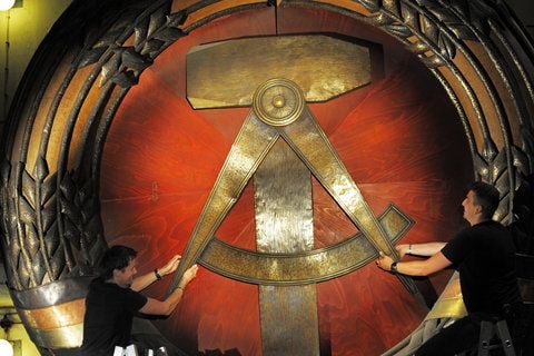 Handwerker zerlegen ein DDR-Wappen. Vielen Menschen gingen Kenntnisse über die DDR verloren, dem soll Schau entgegen gewirkt werden. (ARCHIVFOTO: DPA)