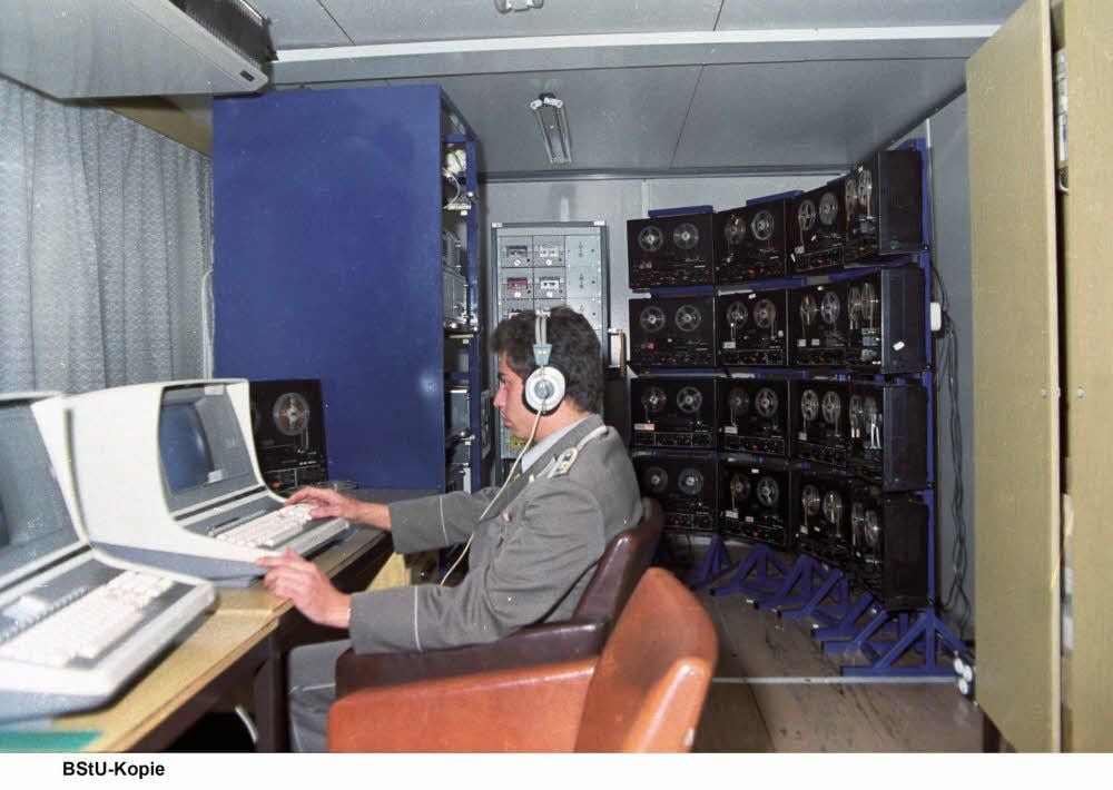 Horch und guck: Stasi-Mitarbeiter beim Abhören von Telefongesprächen, hinten die Tonbänder