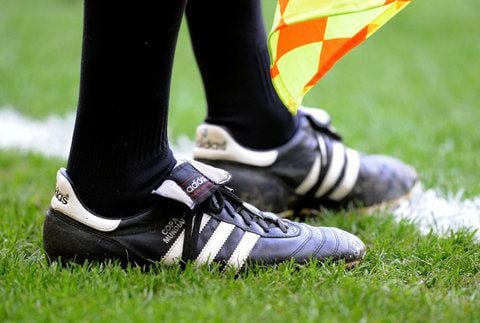 Ein Linienrichter trägt bei einem Bundesliga-Spiel in Mönchengladbach schwarze Adidas-Fußballschuhe. Bei Adidas herrscht Feierlaune: Nach einem Rekordjahr 2011 ist auch das erste Quartal 2012 sehr gut gelaufen. (FOTO: DPA)