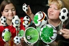 Lachend betrachten die Eier-Malerin Kerstin Dischereit (r) und ihre 10-jährige Tochter Diana am Dienstag (07.03.2006) in Leipzig die von ihnen in Vorbereitung der Fußball-Weltmeisterschaft bemalten und gestalteten Ostereier. (Foto: dpa)