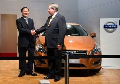 Li Shufu (l.), Vorstandschef der Geely Holding und Lewis Booth, Ford-Finanzvorstand, reichen sich nach der Unterzeichnung des Kaufvertrags vor einem Volvo S60 die Hände. (FOTO: DPA)