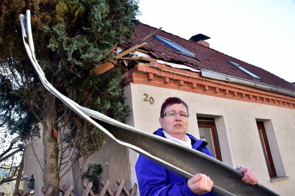 Silke Wahren steht vor ihrem Haus und zeigt eine verbogene Dachrinne.