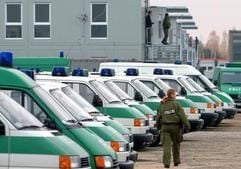 In einem für Polizisten im Castor-Einsatz aufgebauten Container-Dorf geht eine Polizeibeamtin an einer Reihe von Polizeifahrzeugen vorbei (Archivfoto: dpa)