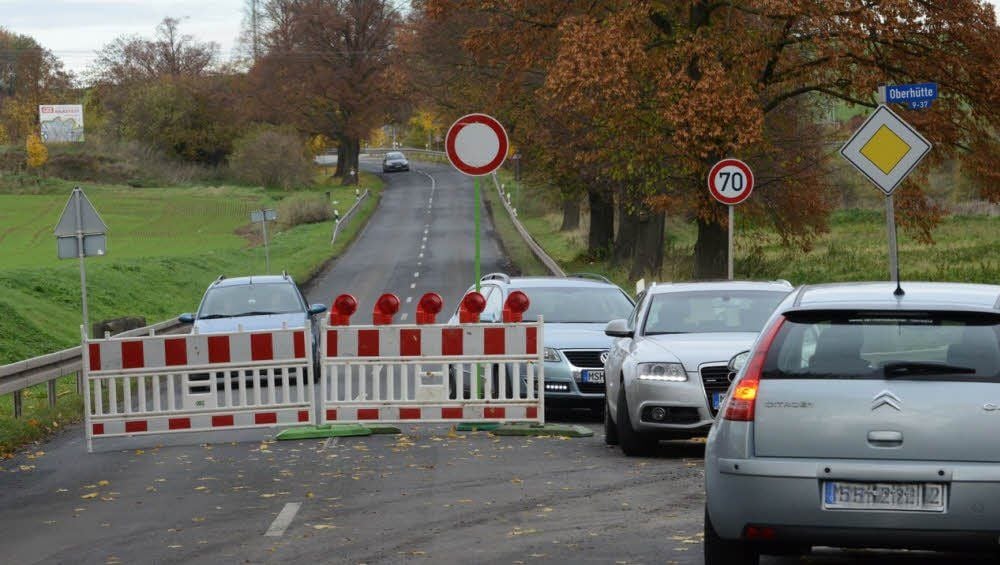 Autofahrer zwängen sich an einer Straßensperrung vorbei