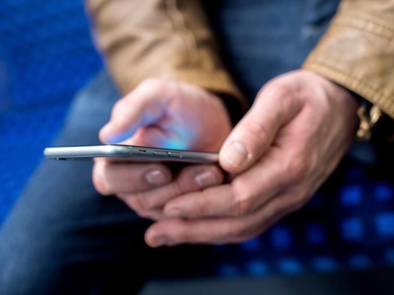 Ein junger Mann sitzt in einer S-Bahn und benutzt dabei sein Smartphone. Foto: Hauke-Christian Dittrich/Archiv