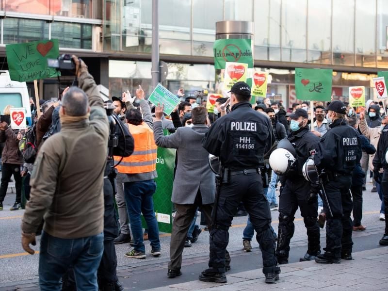 Demonstrationsteilnehmer gestikulieren und rufen in Richtung der Gegendemonstration. Foto: Daniel Reinhardt/dpa/Aktuell