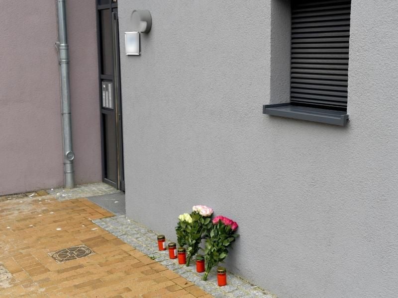 Blumen und Kerzen stehen an einem Mehrfamilienhaus. In dem Gebäude ist eine 17-Jährige nach Messerstichen gestorben. Foto: Carsten Rehder