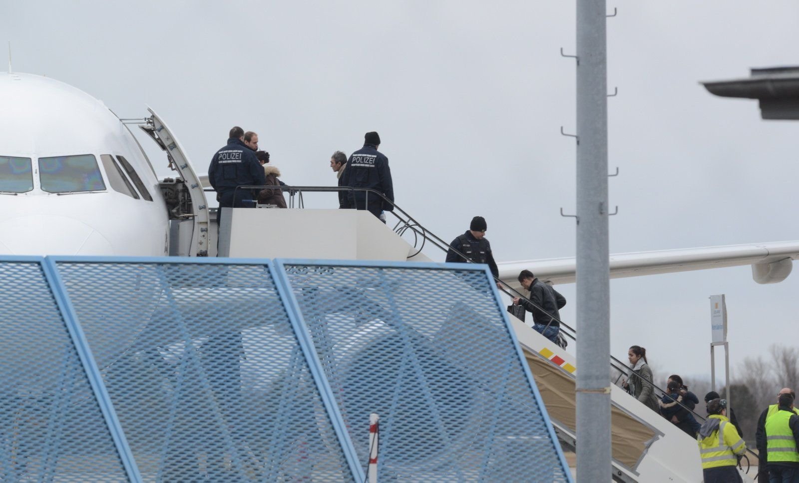 Abgelehnte Asylbewerber steigen unter Aufsicht von Sicherheitsbeamten ein Flugzeug.