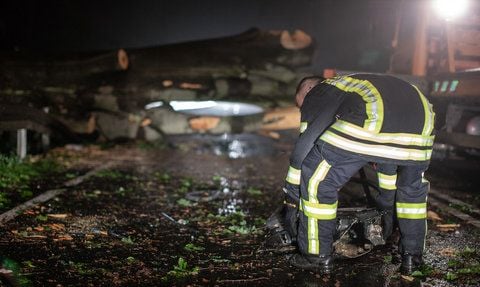 Ein Feuerwehrmann hebt in der Nacht am Samstag Wrackteile eines verünglückten Pkw in einem Wald bei Laußnitz, nördlich von Dresden, auf. (FOTO: DPA)