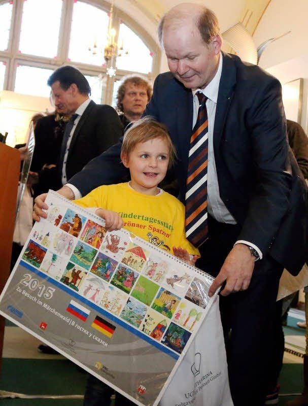 Bernburgs stellvertretender Oberbürgermeister Paul Koller übergibt der kleinen Marit (4) von den „Grönaer Spatzen“ den großen Kalender mit den Märchenmotiven.