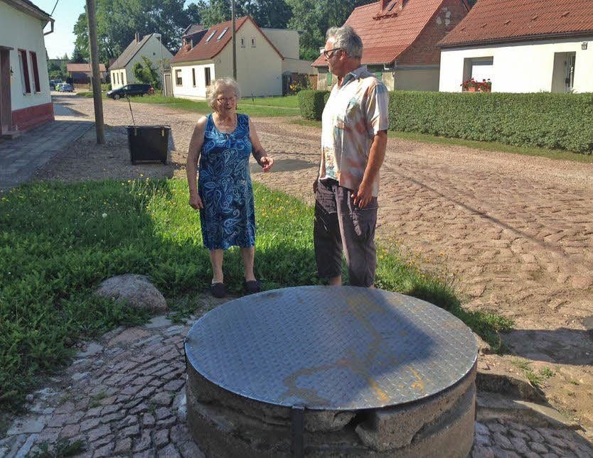 Elli Rühling und Gunter Schneider unterhalten sich vor dem Brunnen, auf dem die Schwengelpumpe stand, die das Straßenbild seit etwa 100 Jahren geprägt hat.