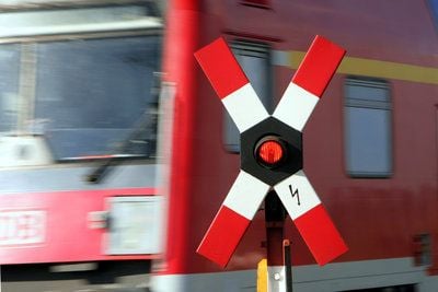 Ein Regionalexpress der Deutschen Bahn AG fährt hinter einem Warnkreuz an einem Bahnübergang vorbei. (FOTO: DPA)
