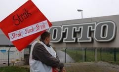 Ein Mitarbeiter des Otto-Versandes in Haldensleben (Ohrekreis) geht mit einem Streik-Schild am Betriebslogo vorbei. (Archivfoto: dpa)