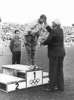NOK-Präsident Karl Ritter von Halt (r) beglückwünscht den ersten deutschen Olympiasieger im 100-m-Lauf der Männer, Armin Hary (M), nach der Siegerehrung (Archivfoto vom September 1960). In einem packenden Finale besiegte Hary während der Olympischen Spiele im September 1960 in Rom den Amerikaner Dave Sim um Nasenlänge. Erst durch die Auswertung des Zielfotos konnte der Sieger ermittelt werden. (Foto: dpa)