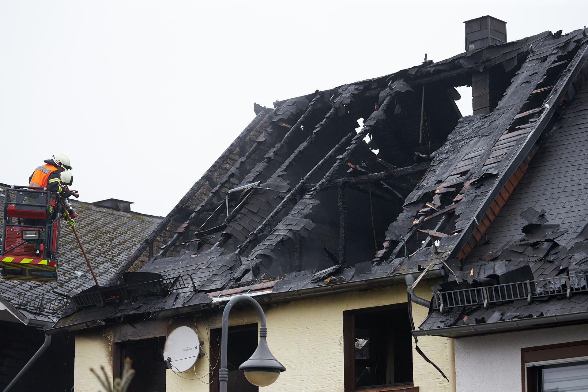 Feuerwehrleute sind nach einem Wohnhausbrand in Mengerskirchen mit Nachlöscharbeiten beschäftigt.