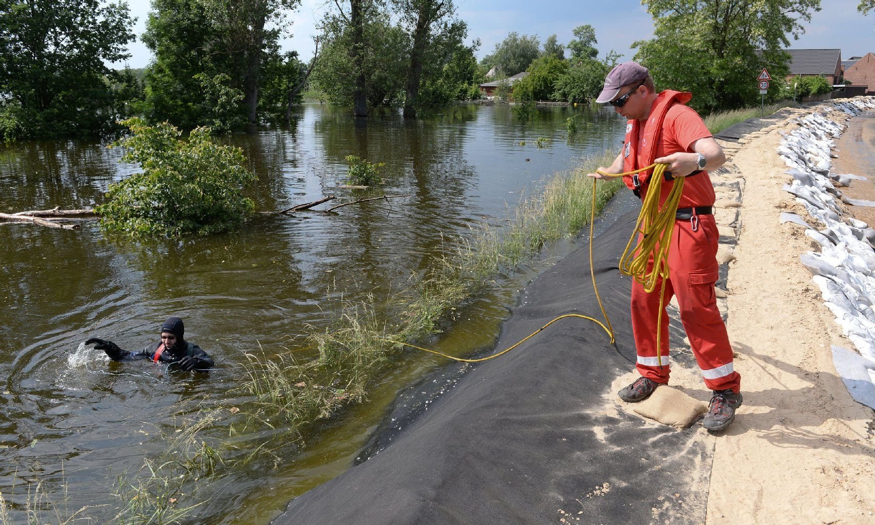 Stefan Untermark (l) und Benjamin Oschmann von der Tauchgruppe der Wasserwacht des DRK Potsdam sammeln am 11. Juni in Breese (Brandenburg) Treibgut das die Deiche beschädigen kann aus dem Wasser.