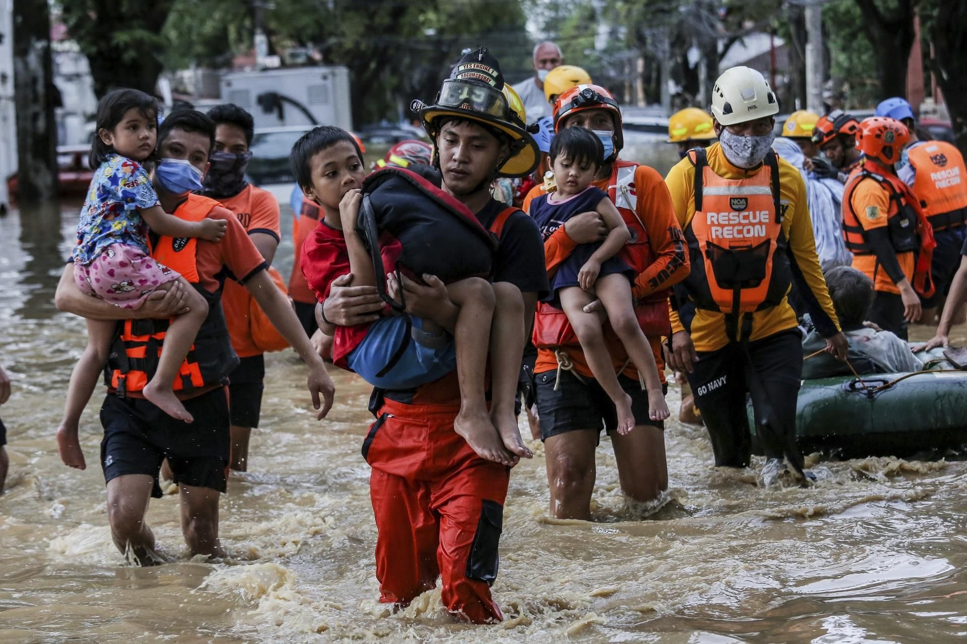 Rettungskräfte tragen Kinder durch eine überschwemmte Straße, die aufgrund des Taifuns überflutet wurde.