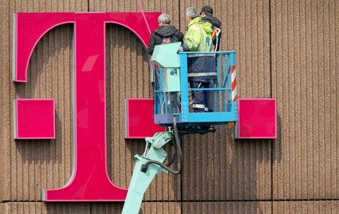 Monteure arbeiten an einem überdimensionalen Telekom-Logo an einer Fassade. (FOTO: DPA)