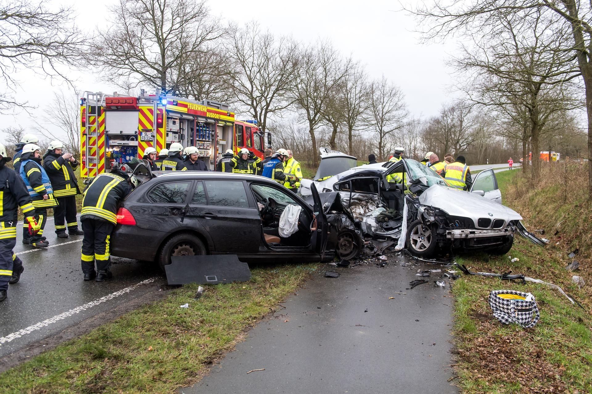 Einsatzkräfte der Polizei und Feuerwehr stehen an der Unfallstelle auf der Kreisstraße zwischen Busdorf und Dannewerk.