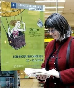 Ein Frau liest vor dem Plakat der Leipziger Buchmesse ein Buch am Montag (15.03.2004) in Leipzig. Am 25.03.2004 beginnt in der Messe die traditionelle Buchmesse. Bis zum 28.03.2004 werden mehr als 2000 Verlage und Editionen aus 29 Ländern auf der Neuen Messe ihre Programme und Neuerscheinungen vorstellen. Themenschwerpunkte sind in diesem Jahr Literaturen aus Mittel- und Osteuropa, Reiseliteratur, Hörbücher sowie Kinder- und Jugendbücher und Comics. (Foto: dpa)