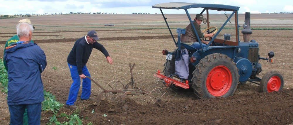 Ein alter Traktor zieht den von Hand zu bedienenden Eisenpflug.