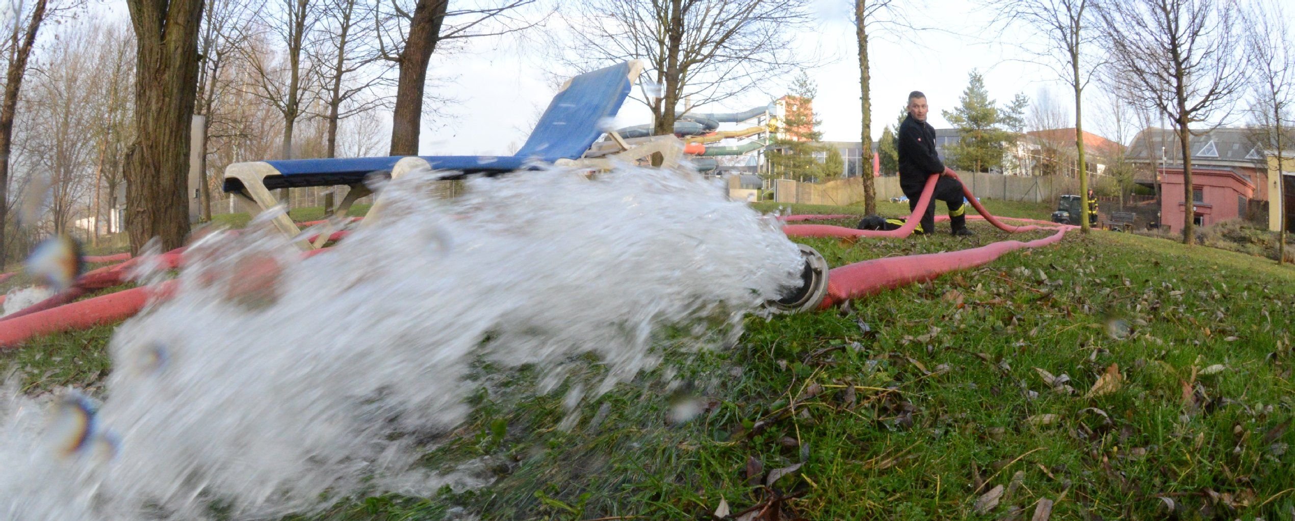 Die Einsatzkräfte der Berufsfeuerwehr-Wache Süd befördern mit Pumpen das Wasser über den Liegebereich hinter dem Bad ins Freie.