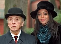 Als Scotland Yard-Beamter Sir John nimmt Schauspieler Eddi Arent in dem Edgar Wallace-Krimi «Die toten Augen von London» mit seiner Schauspielerkollegin Rosalind Baffoe in Berlin an der Beerdigung eines «Gangsters» teil. (Foto: dpa)