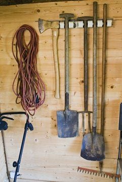 Harke und Schaufel einfach an die Wand klemmen: Mit speziellen Aufhängesystemen werden Gartengeräte platzsparend untergebracht. (Foto: dpa)