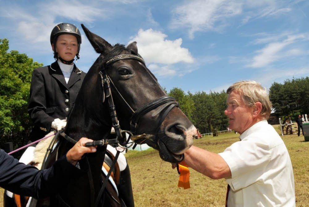 Bernd Himmel (rechts) steckt Leonie Schramms Pferd Ginger die Schleife an.