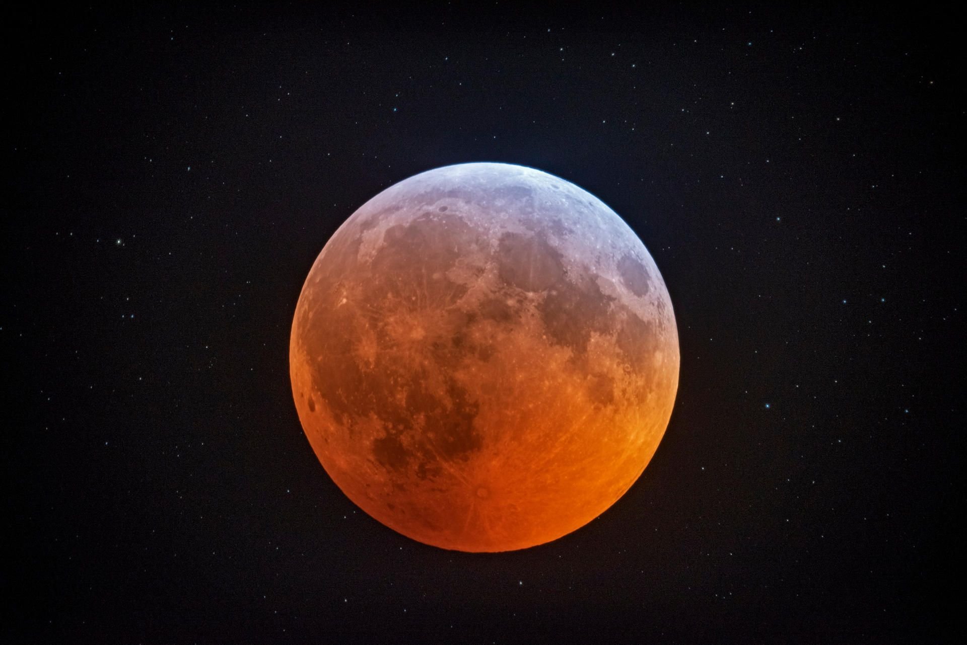 Der Mond leuchtet mit einer rötlichen Farbe vor den Hintergrundsterne.