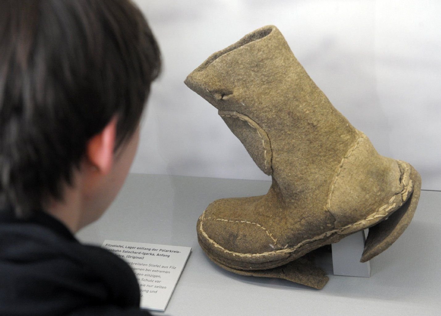 Einen ausgestellten Filzstiefel, der von sowjetischen Strafgefangenen verwendet wurde, betrachtet eine Frau am 11.03.2014 in der Ausstellung "Gulag. Spuren und Zeugnisse" im Zeitgeschichtlichen Forum Leipzig in Leipzig (Sachsen).
