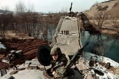 Schwerbewaffnete Ifor-Einheiten bewachen den Einsatz deutscher Pioniere, die eine Brücke bei Visoko (Kroatien) reparieren (Archivfoto vom 13.03.1996). (Foto: dpa)