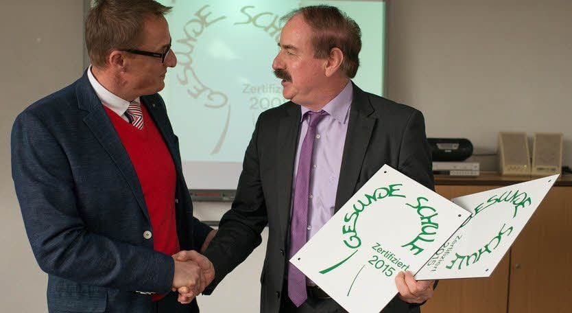 Ulrich Schwabe (re.) übergibt die Schilder an Schulleiter Dirk Gärtner.