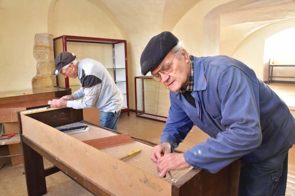 Wolfgang Finke (hinten) und Bruno Schulz richten eine der Vitrinen für das Weinmuseum her.