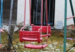 Eine verlassene Kinderschaukel steht vor einem Haus. (Foto: dpa)