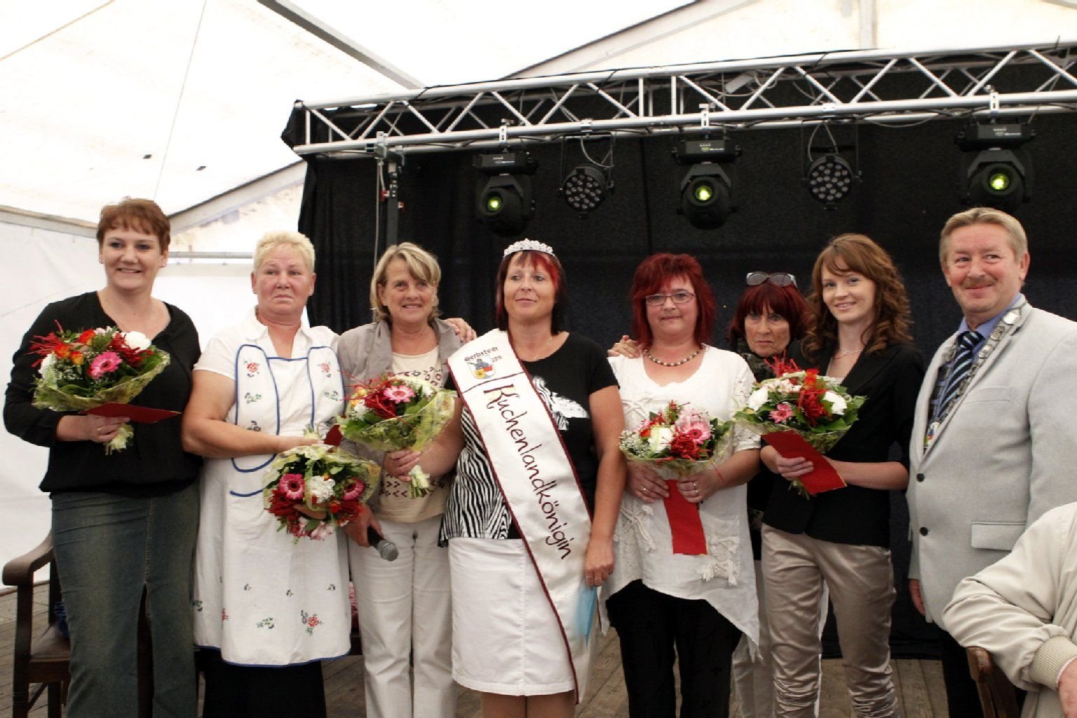Annett Nordmann (Mitte), die 1. Kuchenlandkönigin Gerbstedts, mit den anderen Kandidatinnen sowie Gerbstedts Ortsbürgermeisterin Barbara Höhndorf (3.v.l.), Ortschaftsratsmitglied Karin Zimnik (3.v.r.) und Bürgermeister Siegfried Schwarz
