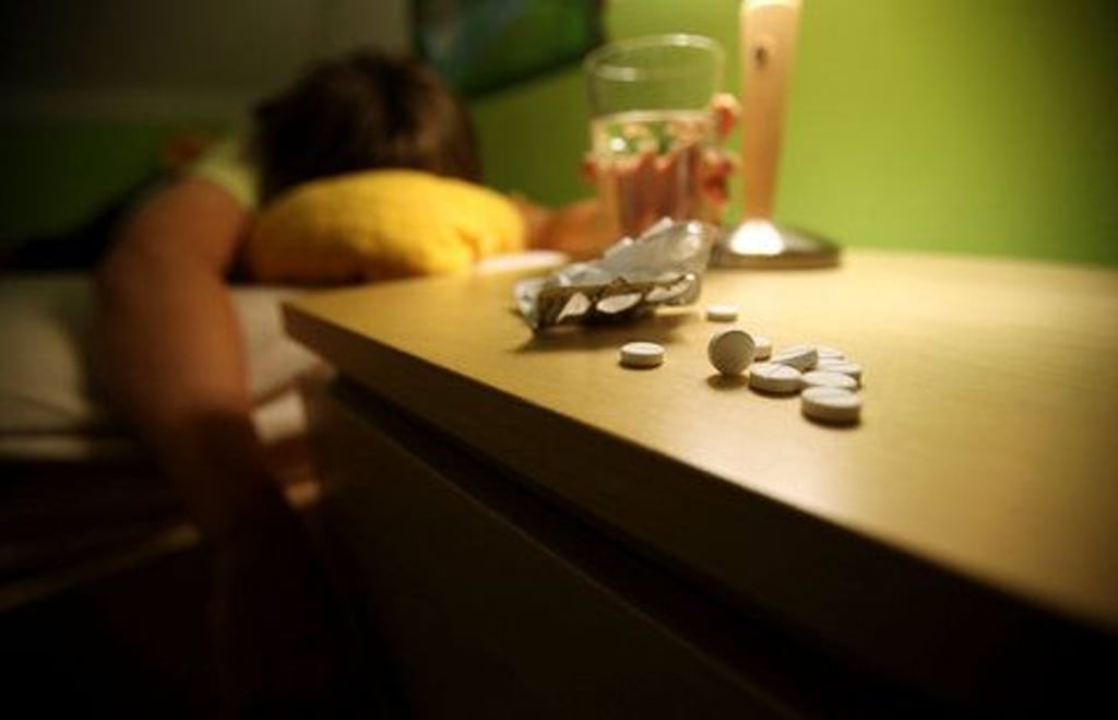 Ein Jugendlicher liegt in seinem Bett, auf dem Nachtisch liegen Schlaftabletten. (FOTO: DPA)