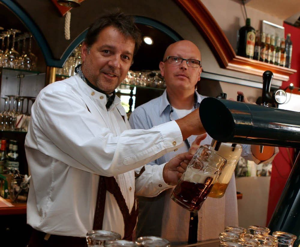 Die Gastwirte Lutz Eisfeld (vorn) und Thomas Holst haben sich fürs Foto schon mal bayrisch-zünftig gekleidet. Beide laden am letzten September-Wochenende zum großen Oktoberfest auf den Karlsplatz ein.