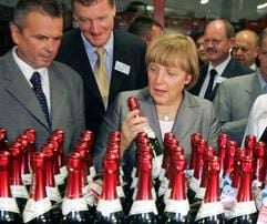 Angela Merkel und der Geschäftsführer der Rotkäppchen-Mumm-Sektkellereien GmbH in Freyburg (Sachsen-Anhalt), Gunter Heise (l.), betrachten Sektflaschen auf einem Fließband in der Freyburger Sektkellerei (Archivbild vom 23.08.2004). (Foto: dpa)