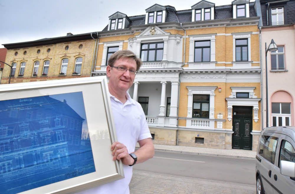 Uwe Woytinas vor der Promenade 15 mit einem Bild, das dieses Haus vor seiner Sanierung zeigt.