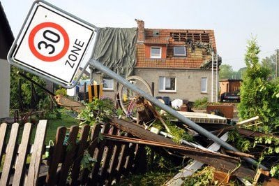 Ein umgeknicktes Verkehrsschild liegt in Plate vor einem Haus mit halb abgedecktem Dach. Ein Unwetter hatte in dem Ort südöstlich von Schwerin am Donnerstag abend schwere Schäden von rund 3,5 Millionen Euro angerichtet. (FOTO: DPA)