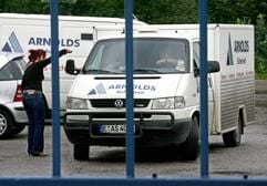 Ein Geldtransporter der Sicherheitsfirma Arnolds wird in Essen hinter einem Gittertor abgefertigt. (Foto: dpa)