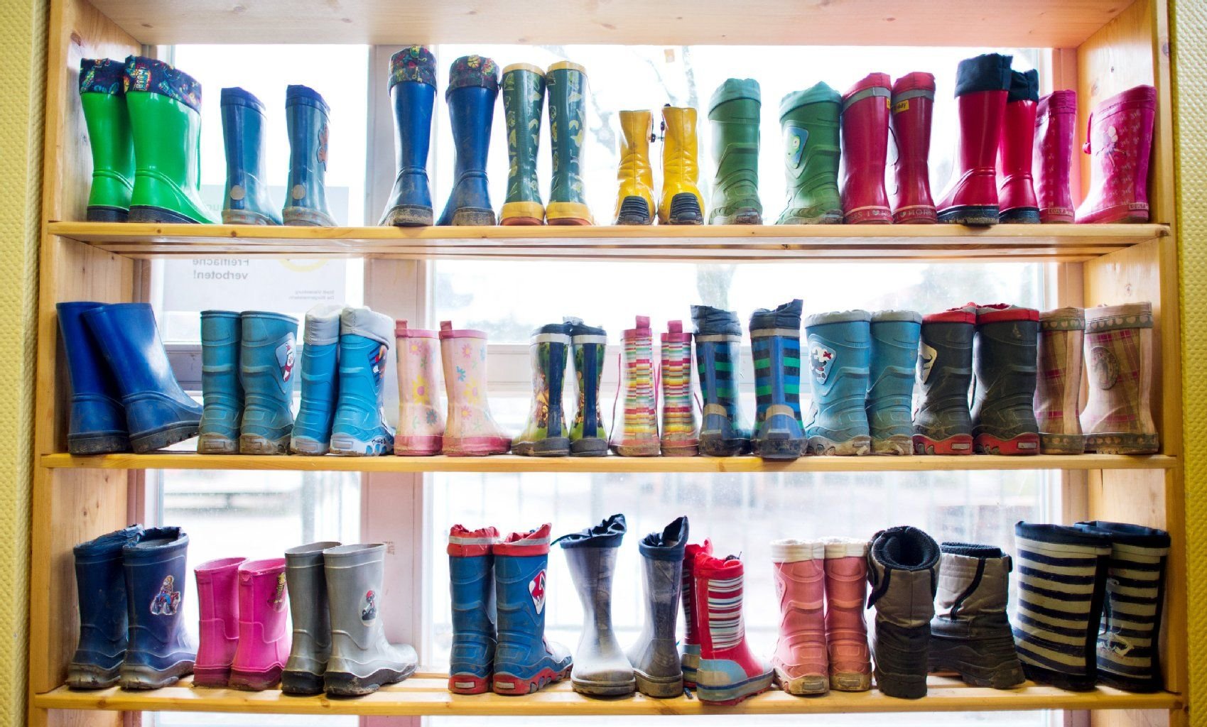 Gummistiefel stehen im Regal einer Kindertagesstätte.