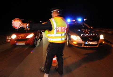 Ein Polizist kontrolliert am frühen Sonntagmorgen in Friedrichshafen am Bodensee ein Fahrzeug. Die Polizei hat in der ganzen Nacht zum Sonntag im Bondenseekreis Fahrzeugkontrollen durchgeführt. (FOTO: DPA)
