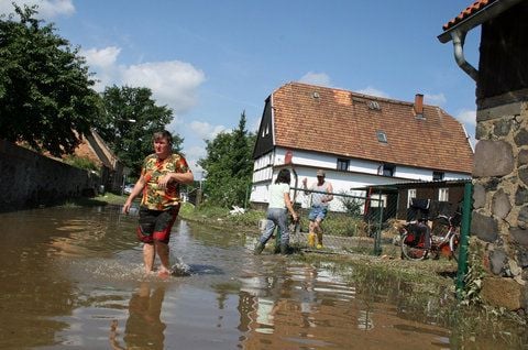 Einwohner der Thomas-Müntzer-Straße in Hagenwerder südlich von Görlitz laufen durch die überflutete Straße. (FOTO: DPA)