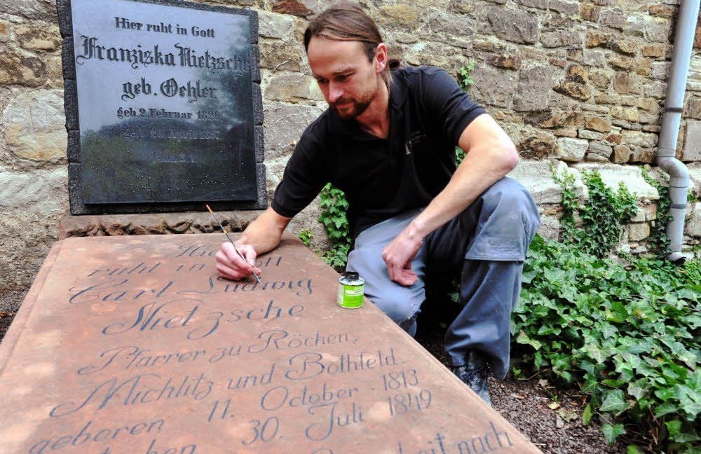 Daniel Kittler restauriert vor dem Geburtstag von Carl Friedrich Nietzsche die Grabplatte an der Röckener Kirche.